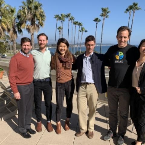 Five students stand with professor in group on terrace overlooking ocean