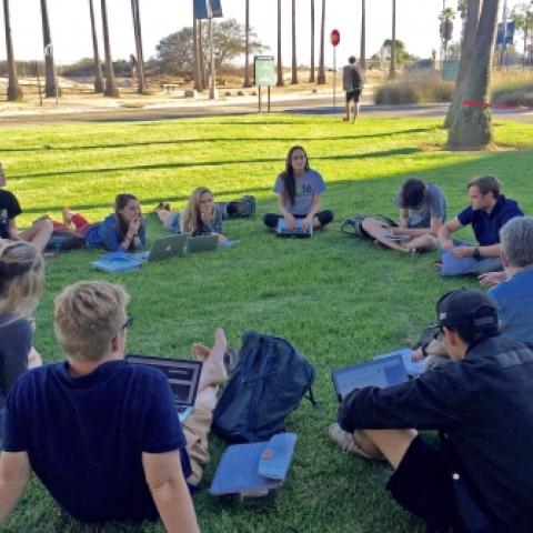 Group of students sitting in circle on grass